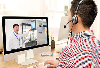 Mann mit einem Headset vor einem Computer bei einer virtuellen Führung