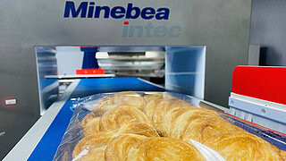 L'image montre des biscuits emballés sur un tapis roulant d'un détecteur de métaux Minebea Intec.