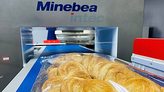 La imagen muestra galletas empaquetadas en una cinta transportadora de un detector de metales Minebea Intec