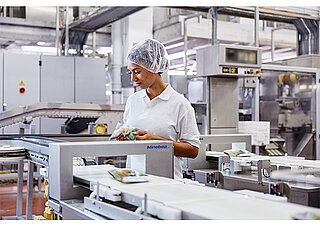 a woman in front of a inspection system in the dairy prodcution