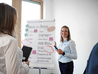 Kollegen bei Minebea Intec die gemeinsam auf ein Flipchart schauen und ein Projekt besprechen