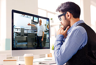 Mann sitzt vor einem Computer und nimmt an einer virtuellen Führung teil
