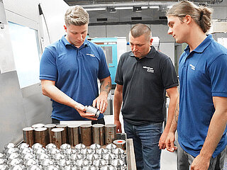 An experienced Minebea Intec employee explains to trainees and interns the next step in production