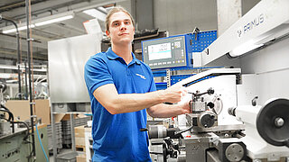 Das Bild zeigt einen Auszubildenden von Minebea Intec bei der Arbeit in der Produktionsstätte in Hamburg