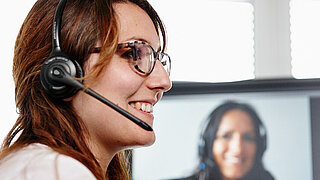 Femme avec un casque d'écoute dirigeant un séminaire en ligne.