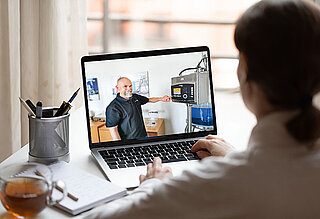 Frau, die vor einem Computer sitzt und an einer virtuellen Führung teilnimmt