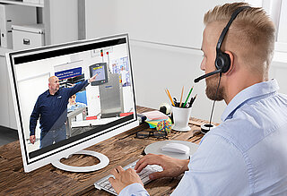 Man with headset watching someone operating a machine